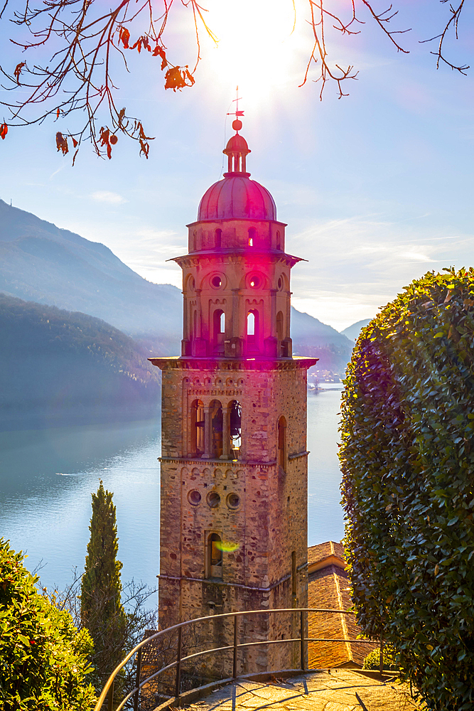 Church Tower Santa Maria del Sasso with Sunlight and Bare Tree and Mountain on Lake Lugano in Morcote, Ticino, Switzerland, Europe