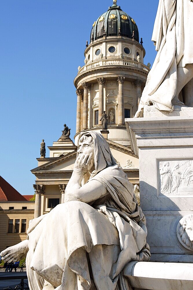 Detail of the monument to german poet Friedrich Schiller in Gendarmenmarkt Square in Berlin and French Dome in the background. Selective focus