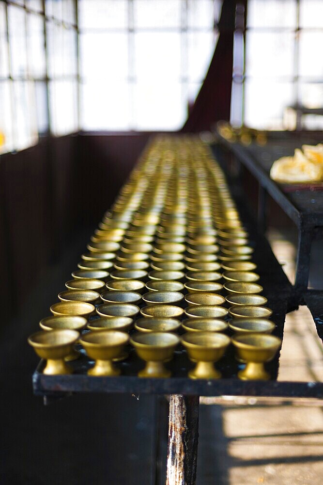 Rows of traditional Buddhist butter lamps lined up in a storage room at the Rumtek Monastery in Gangtok, Sikkim, India, Asia