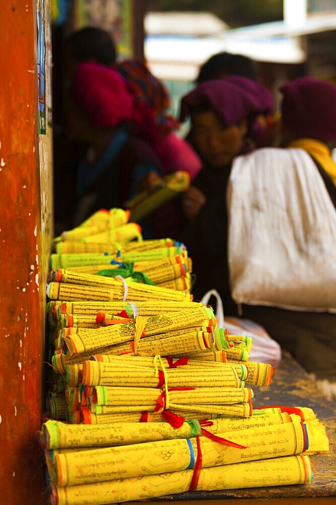 Monks gather to purchase mass produced yellow Tibetan prayer scrolls at a store in Zhongdian, China, Asia