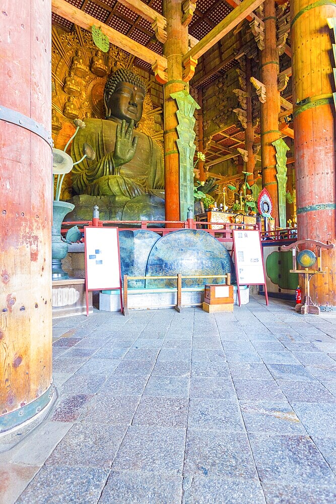 Angled profile of the world's largest bronze Buddha statue inside the Great Buddha Hall, Daibutsuden, at Todai-ji temple in Nara, Japan. Vertical Interior