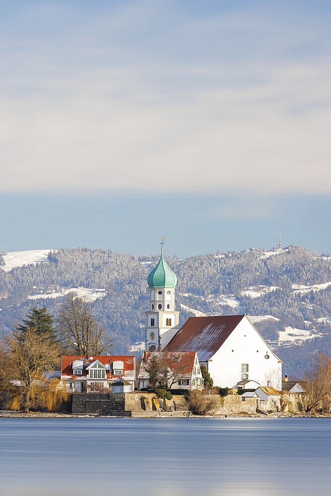 St George's Church with green tower in front of snow-covered Pfänder, surrounded by village houses, moated castle, Lake Constance, Bavaria, Germany, Europe