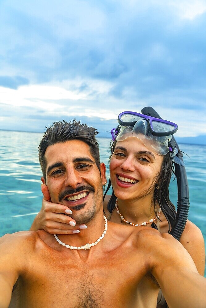 Happy couple taking a selfie while snorkeling in tropical turquoise water, enjoying their vacation in a beautiful seascape