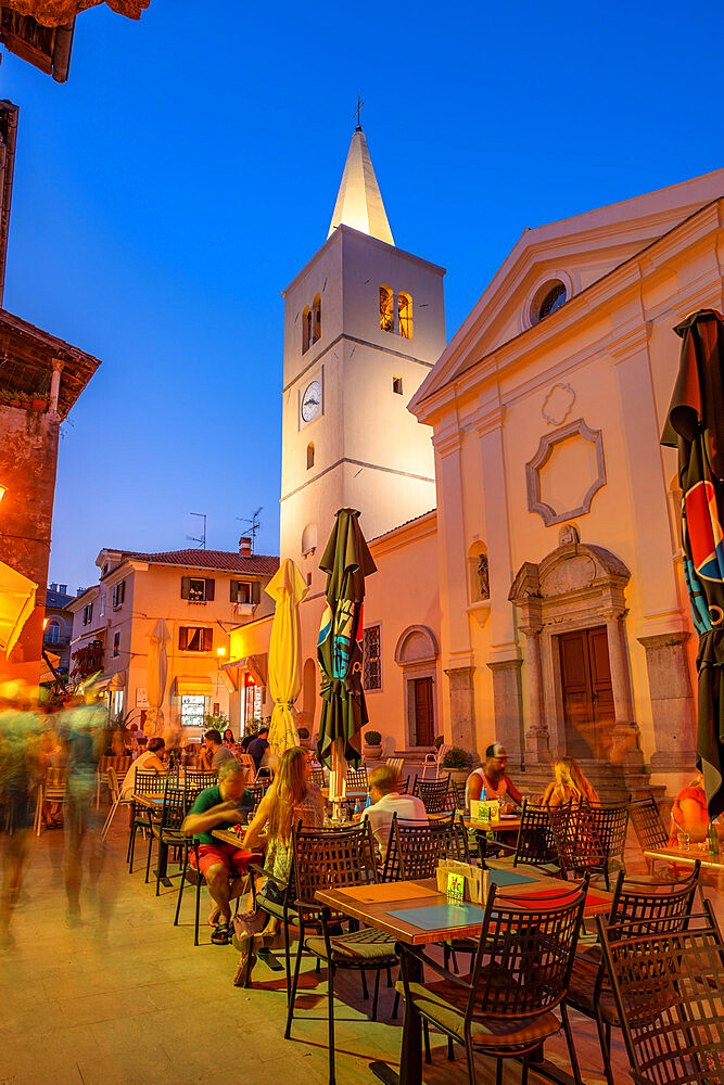 View of St. George's Church and alfresco eating at dusk in Lovran village, Lovran, Kvarner Bay, Eastern Istria, Croatia, Europe