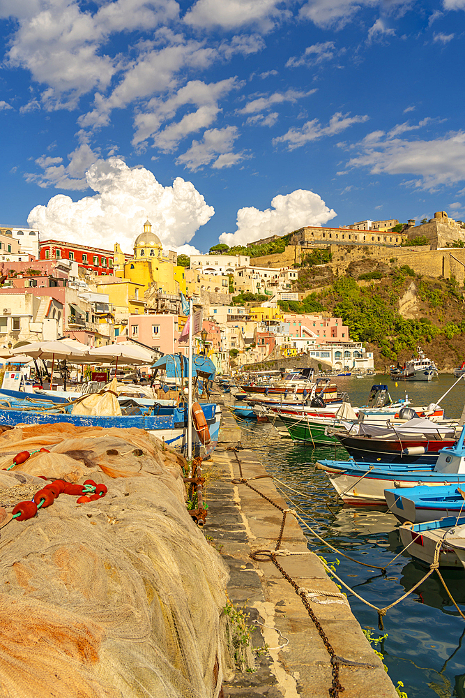 View of fishing nets, boats in Marina di Corricella and Eglise Santa Maria delle Grazie in background, Procida, Phlegraean Islands, Gulf of Naples, Campania, Southern Italy, Italy, Europe