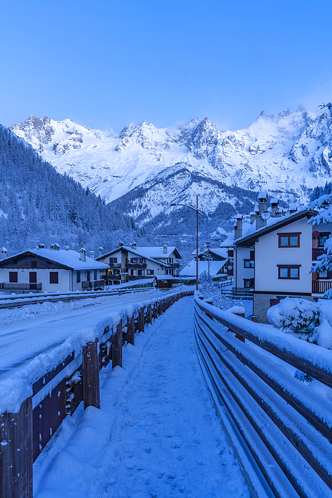 View of chalets and snow covered mountains in Courmayeur before dawn during winter, Courmayeur, Aosta Valley, Italy, Europe