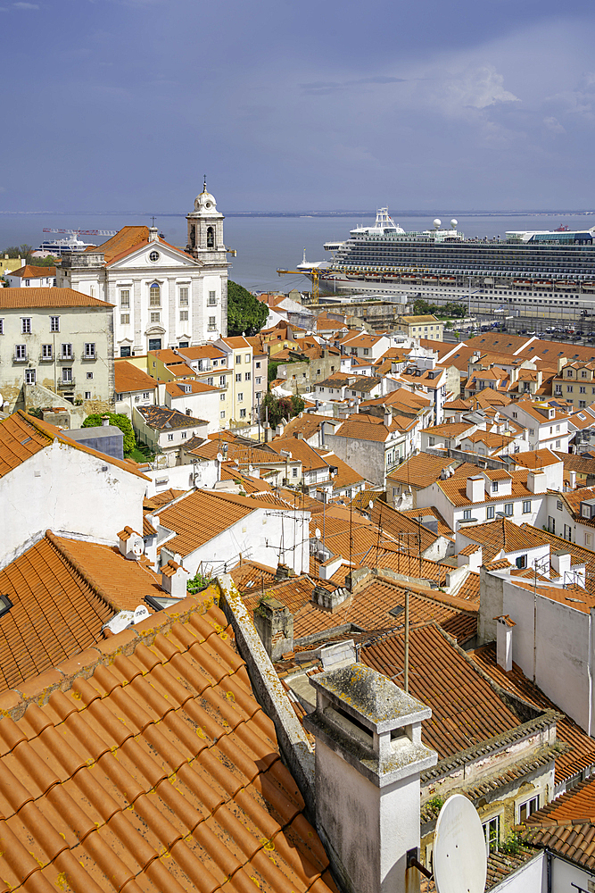 View of cruise ship in port and terrakotta rooftops in Alfama, Alfama District, Lisbon, Portugal, Europe