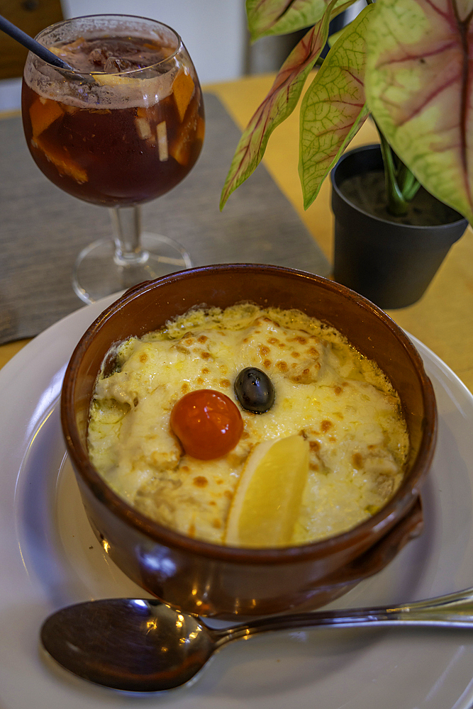 View of glass of Sangria and Bacalhau Com Natas traditional Portuguese dish in restaurant, Alfama District, Lisbon, Portugal, Europe