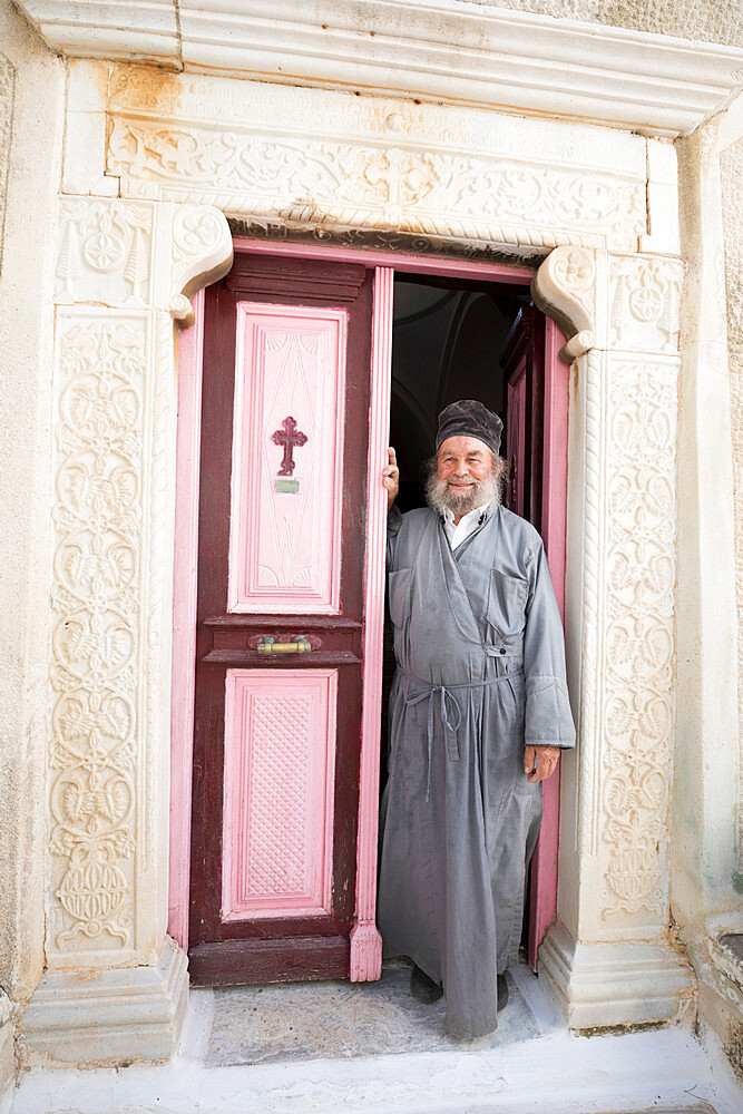 Greek Orthodox priest standing in doorway of Moni Taxiarchon Monastery, Serifos, Cyclades, Aegean Sea, Greek Islands, Greece, Europe