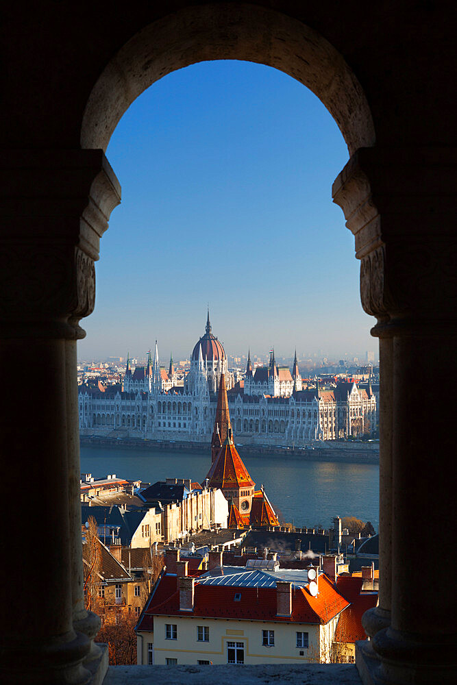 Parliament (Orszaghaz) and River Danube through arches of Fishermen's Bastion (Halaszbastya), UNESCO World Heritage Site, Buda, Budapest, Hungary, Europe