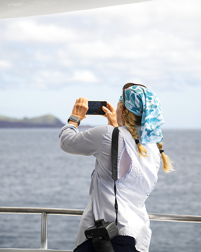 Tourist enjoying view from yacht, Isla Bartholomé, Galapagos Islands, Ecuador