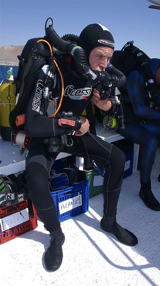 Diver on board dive boat checking equipment    