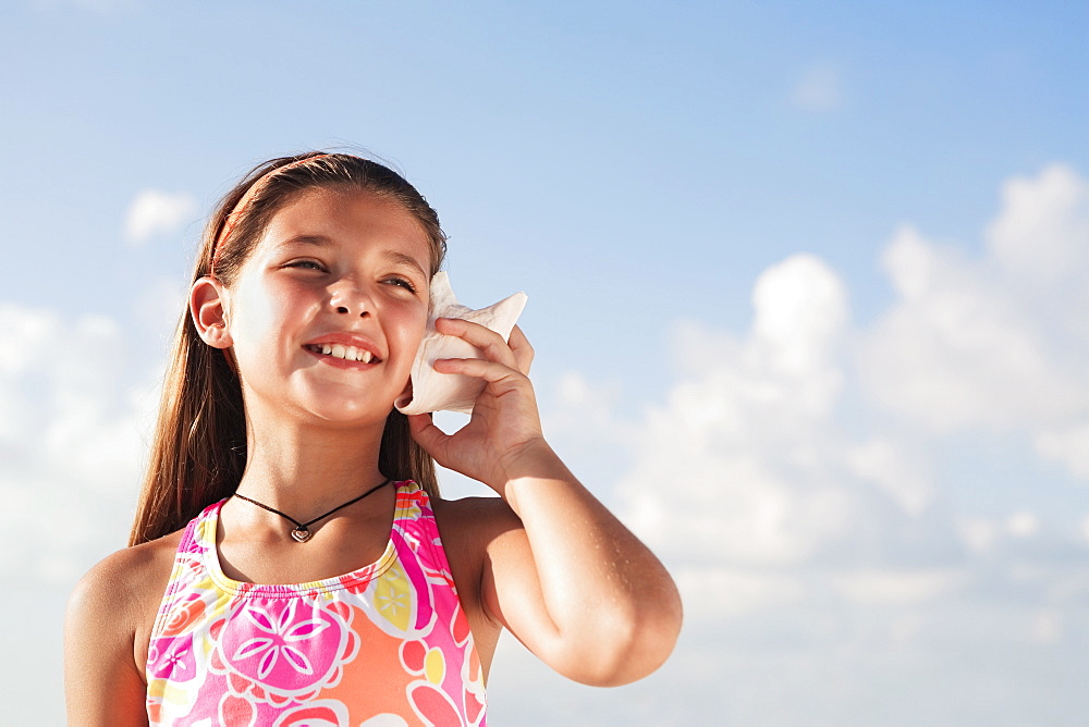 Girl holding conch shell to ear