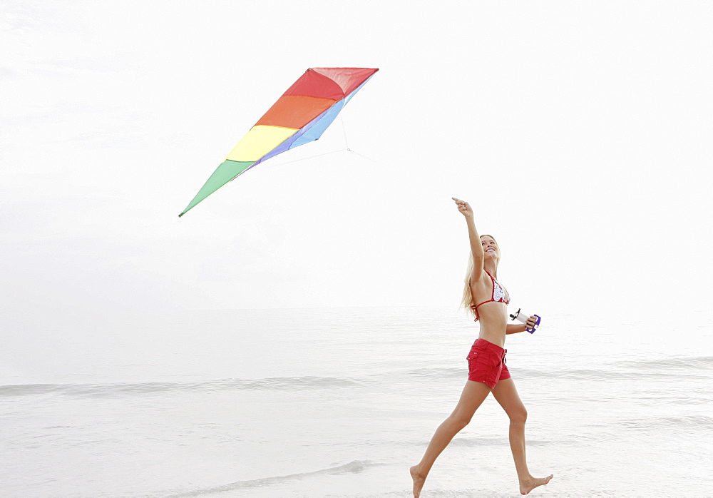 Young woman flying kite on beach