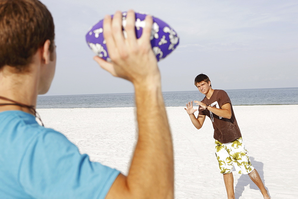 Friend playing football on beach