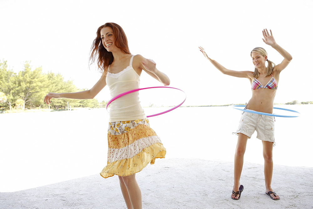 Young women hula hooping on beach