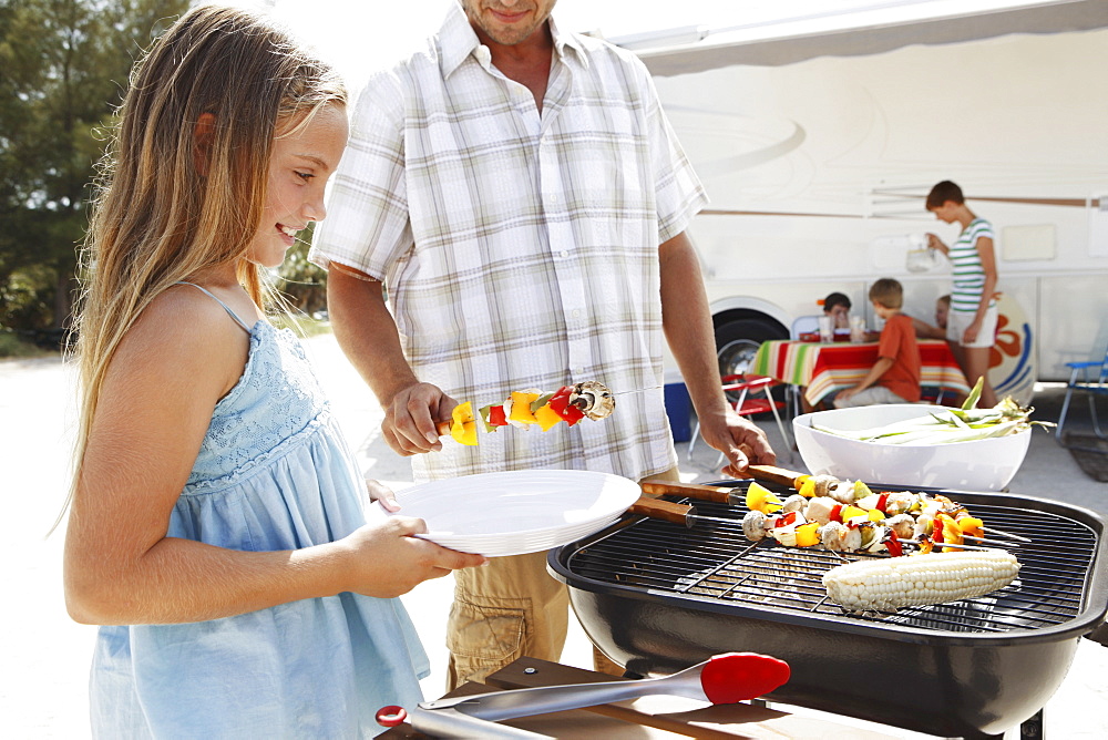 Man grilling dinner for family on beach