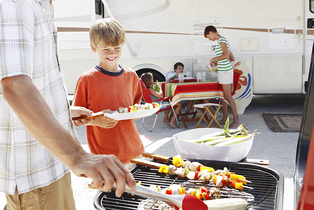 Man grilling dinner for family on beach