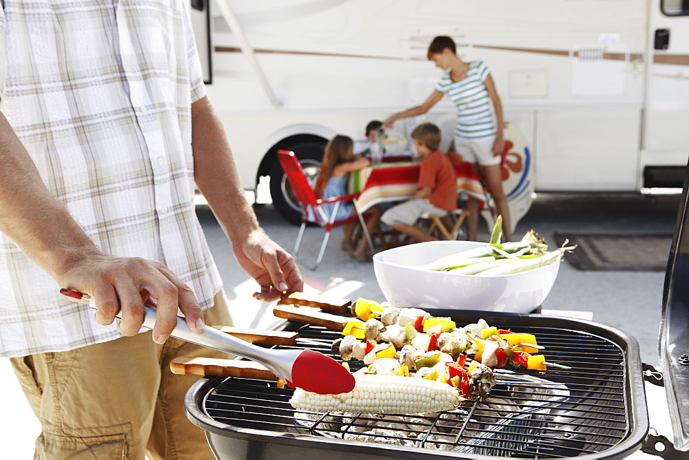 Man grilling dinner for family on beach