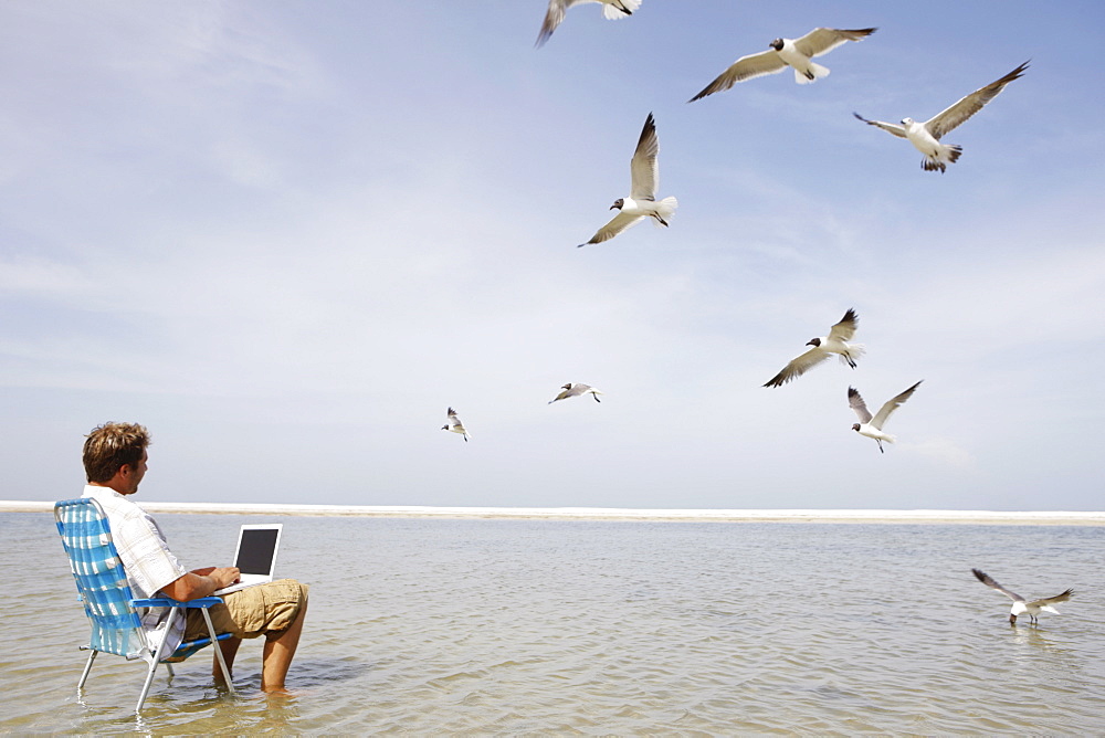 Man using laptop in middle of water