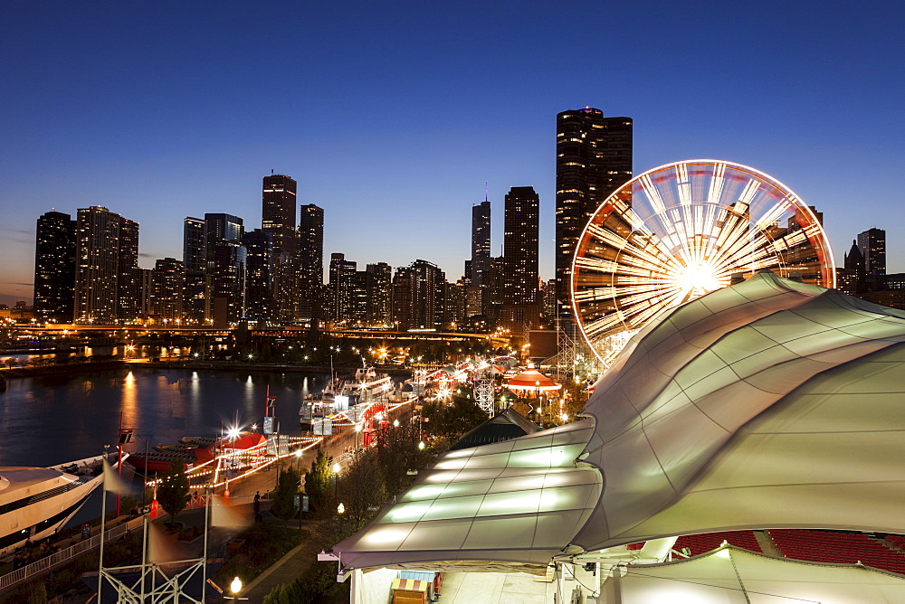 Illuminated ferris wheel with skyscrapers in background, Chicago, Illinois 