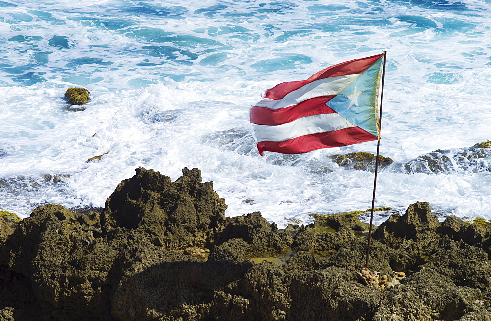 Puerto Rico, Old San Juan, Puerto Rican flag on rock with sea in background