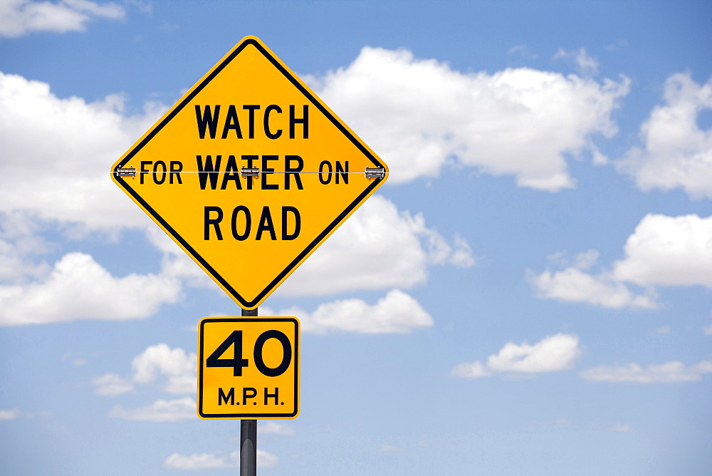 Road sign against cloudy sky