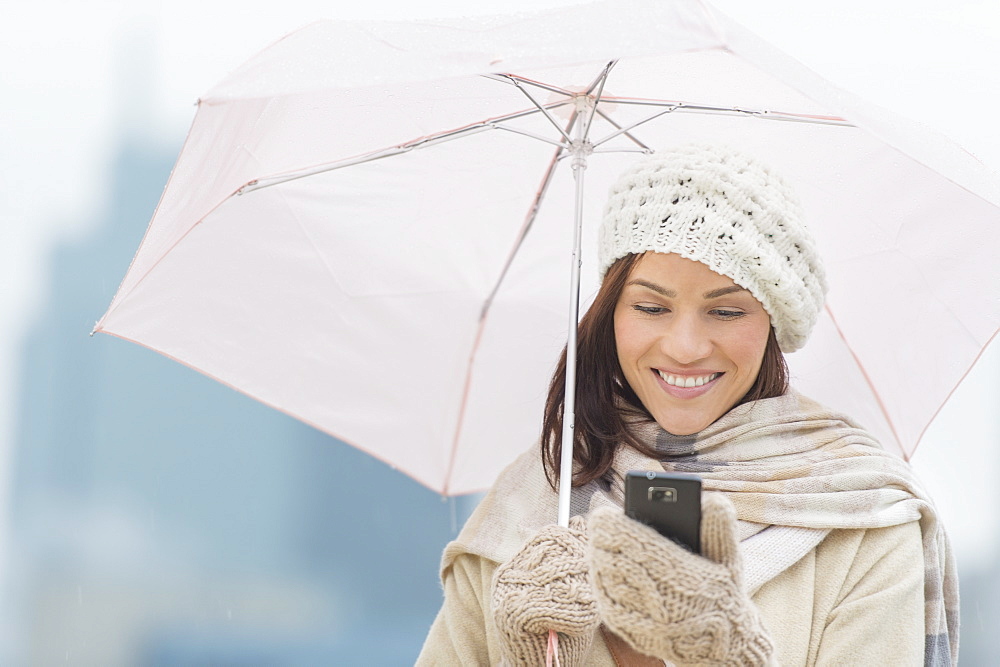 Woman with umbrella using phone