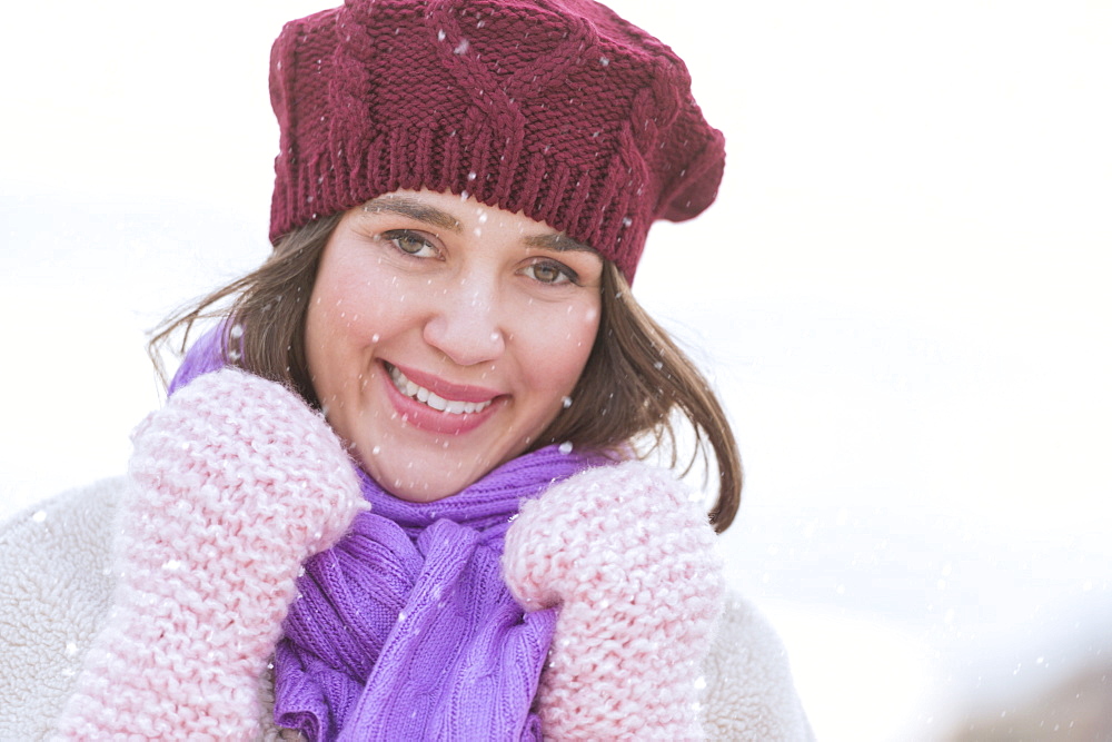 Portrait of young woman wearing knit hat, gloves and scarf