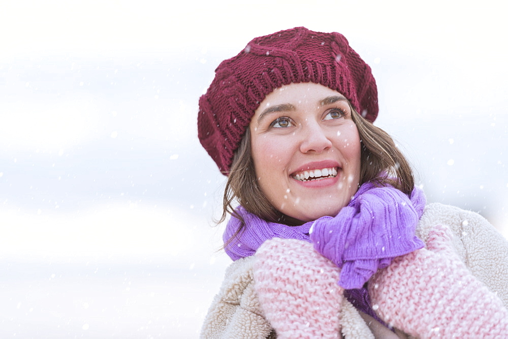 Portrait of young woman wearing knit hat, gloves and scarf