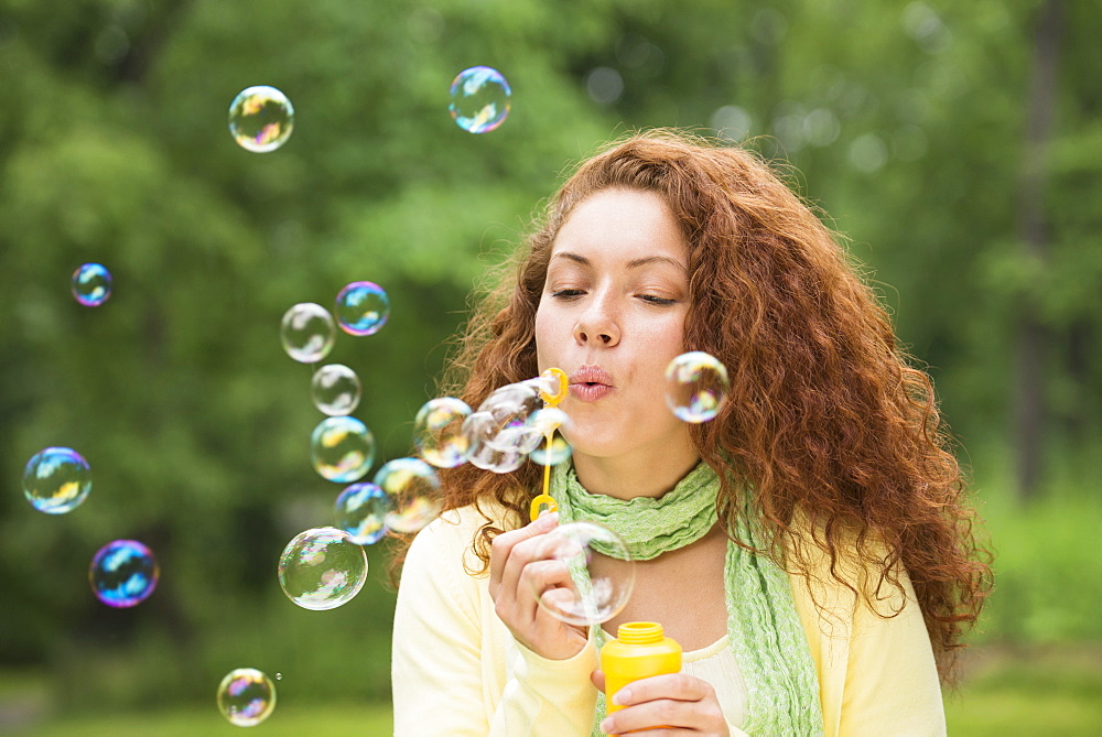 Young woman blowing bubbles in park