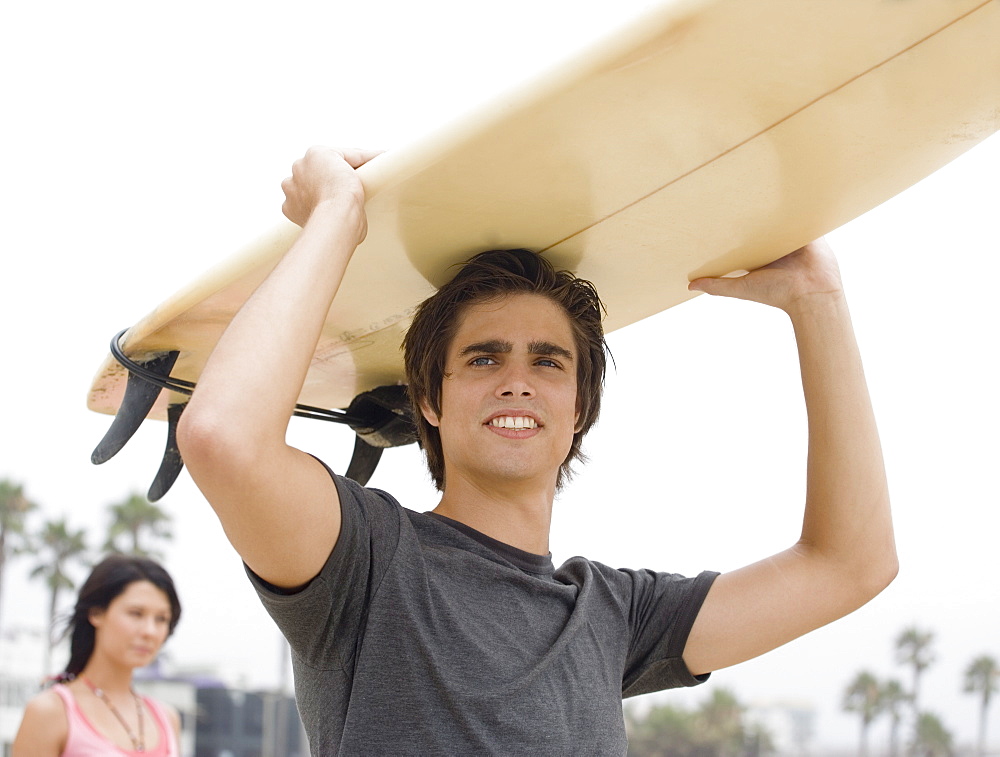 Man carrying surfboard on head 