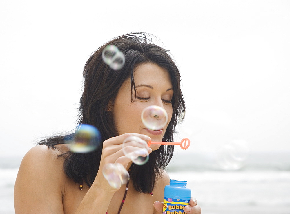 Woman blowing bubbles at beach