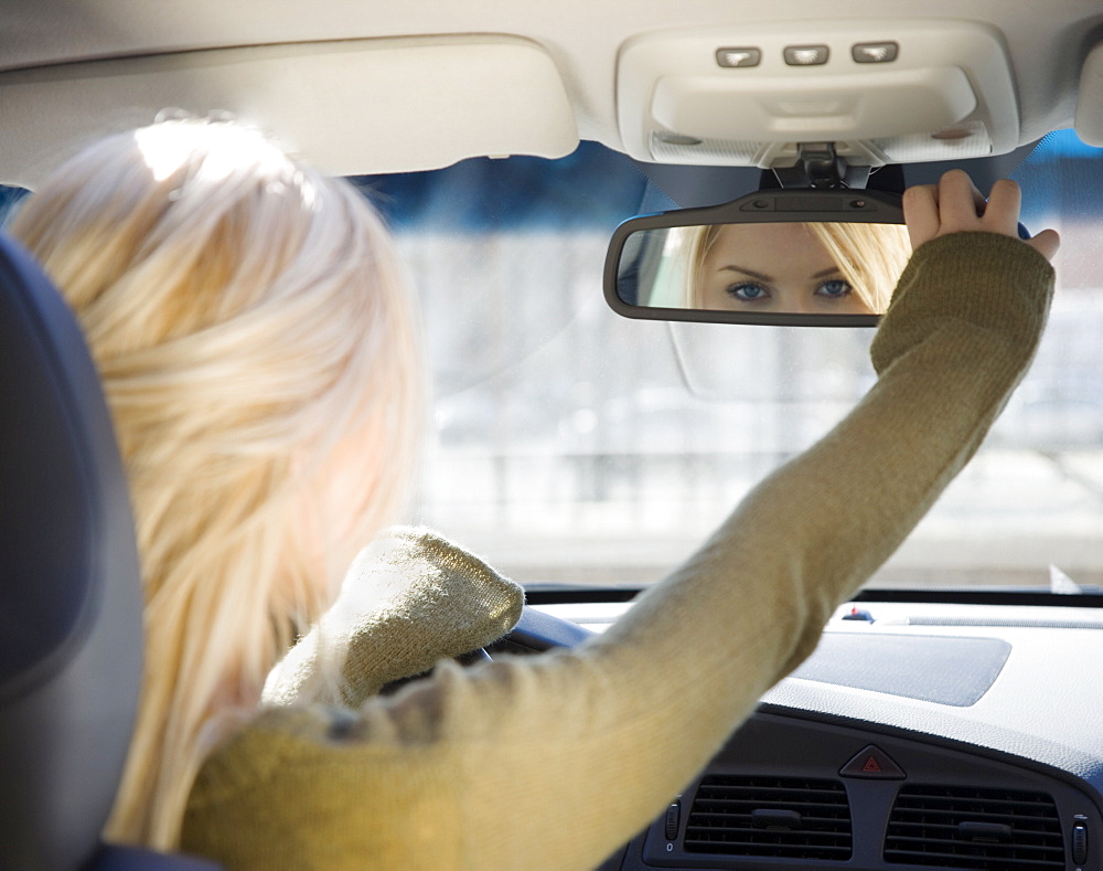 Woman adjusting car rear view mirror