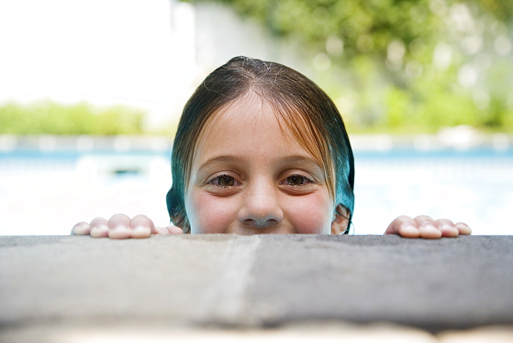 Girl peeking over edge of swimming pool