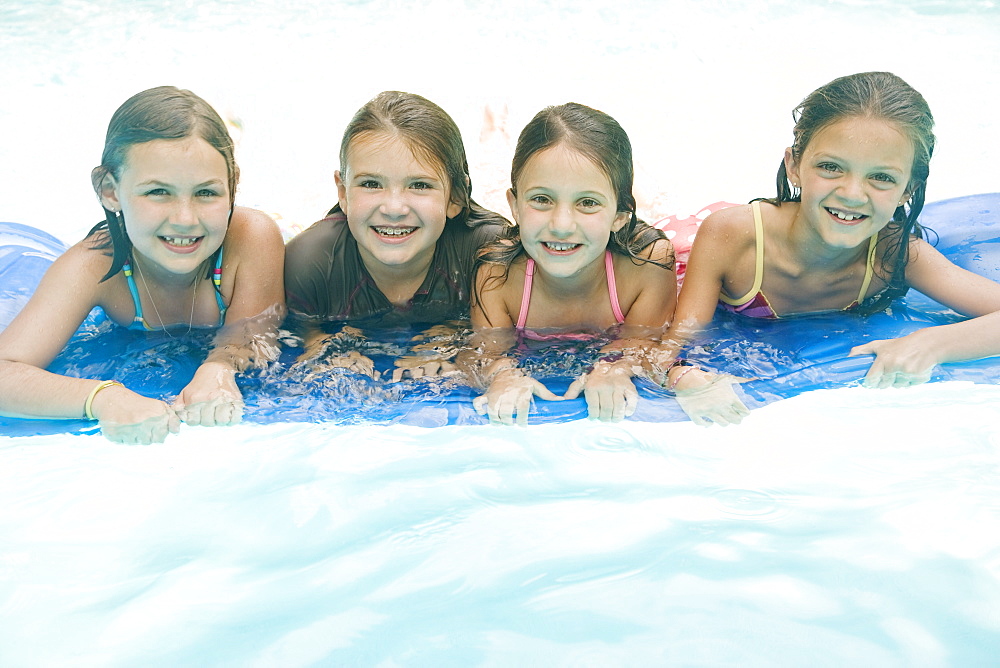 Girls resting on inflatable raft in swimming pool