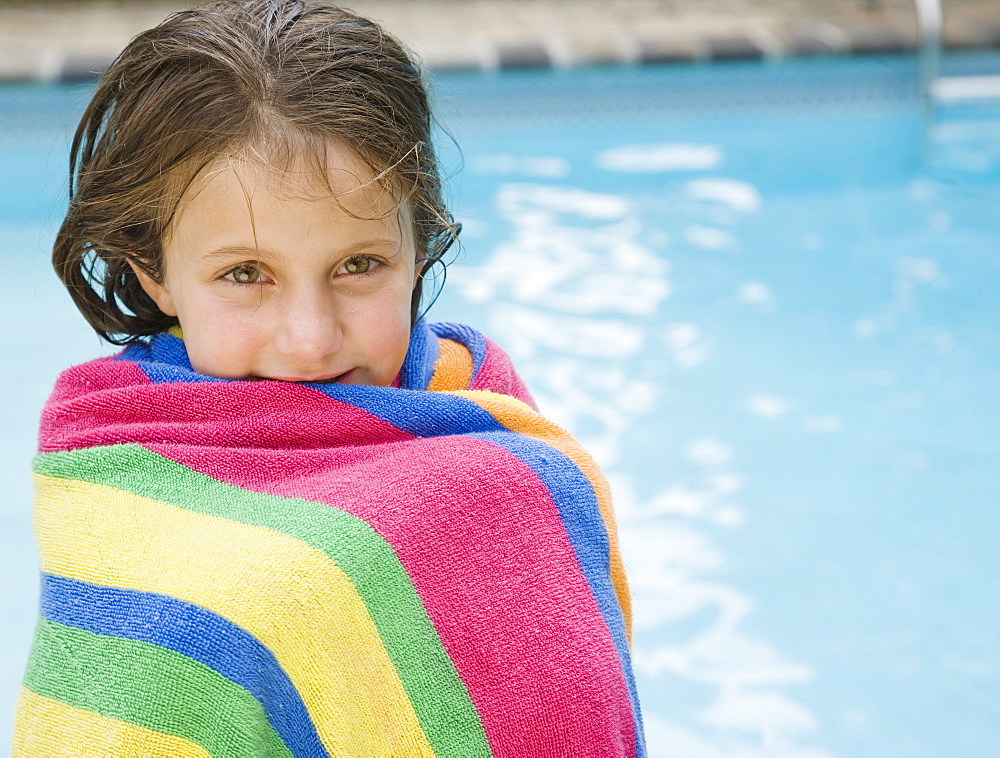 Girl wrapped in a towel at edge of swimming pool