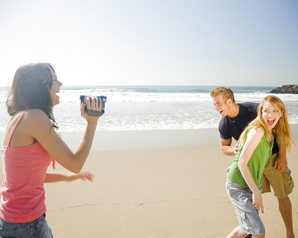 Woman video recording friends at beach