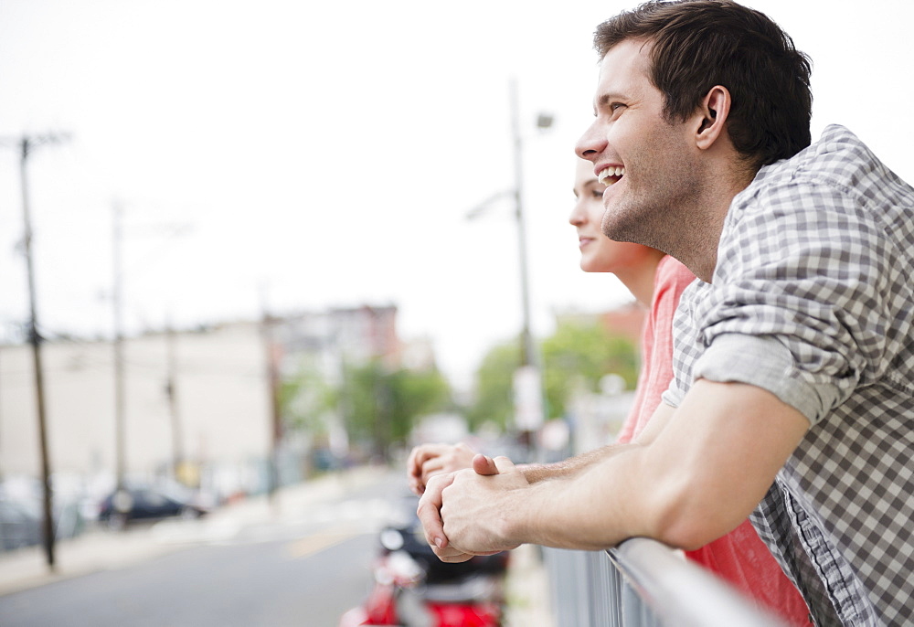 USA, New Jersey, Jersey City, Profile of happy young couple leaning on fence, USA, New Jersey, Jersey City