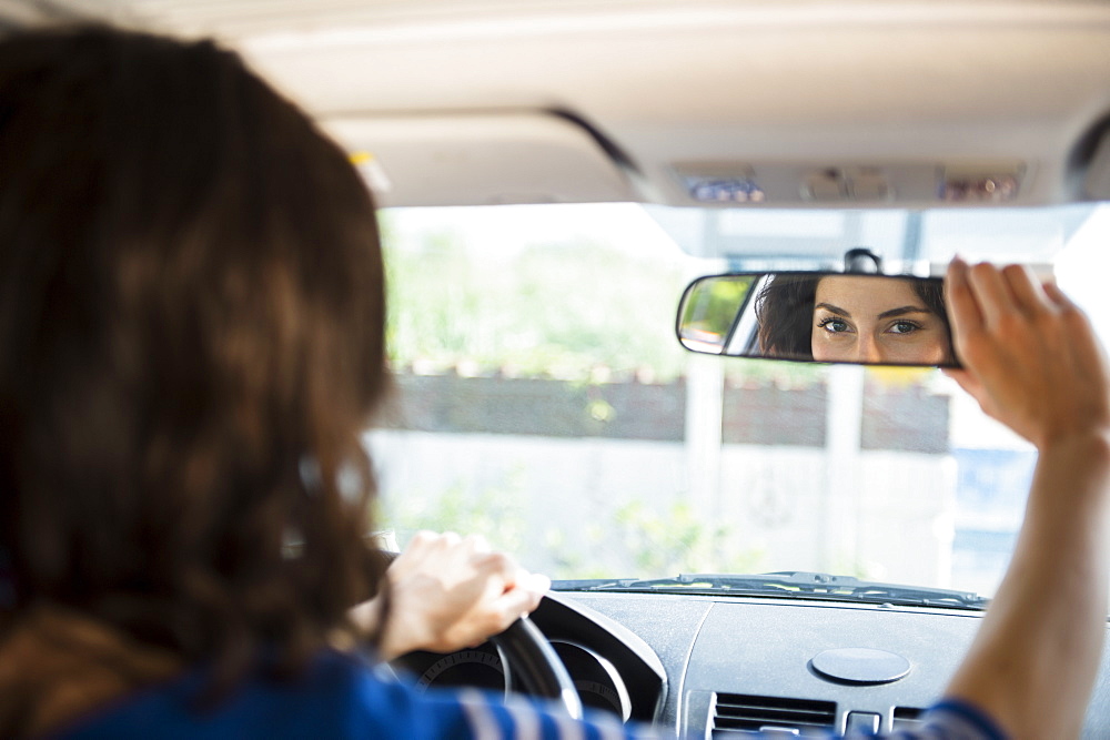 Woman adjusting rear view mirror in car