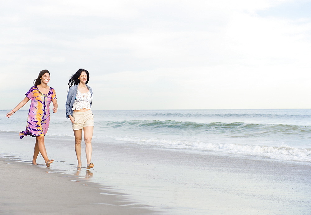 Two women walking on beach, Rockaway Beach, New York