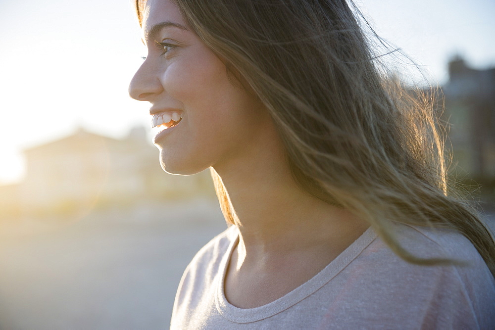 Profile of smiling woman at sunset, Rockaway Beach, New York