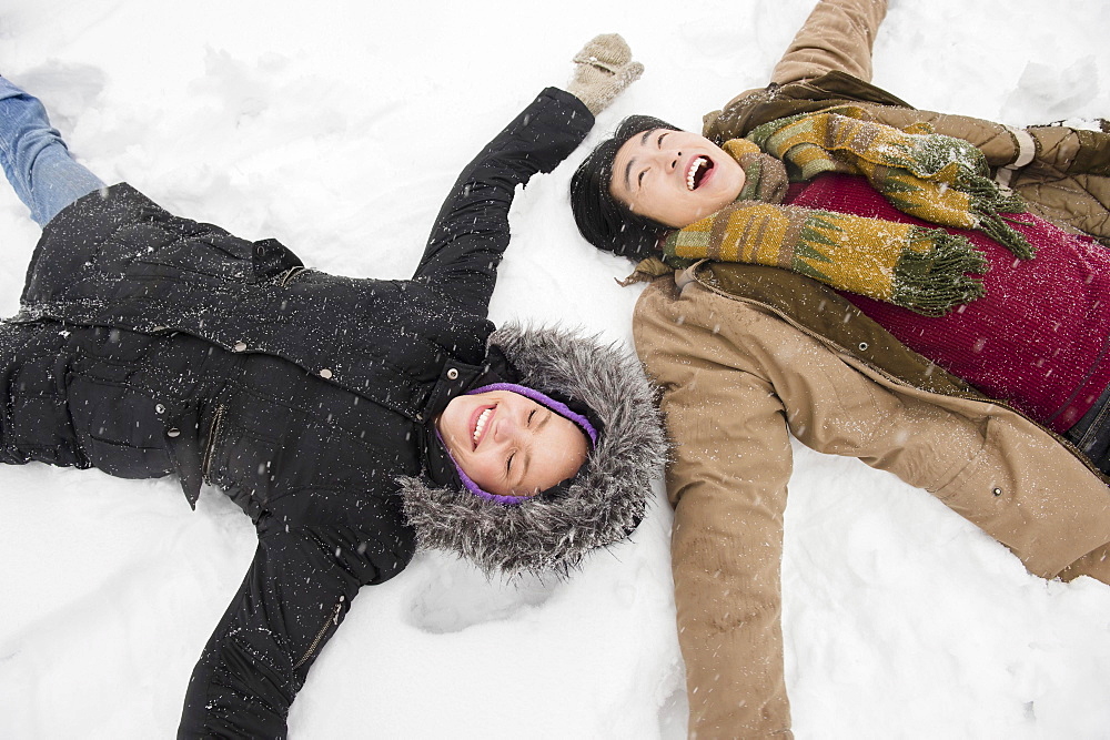 Two young people making snow angels