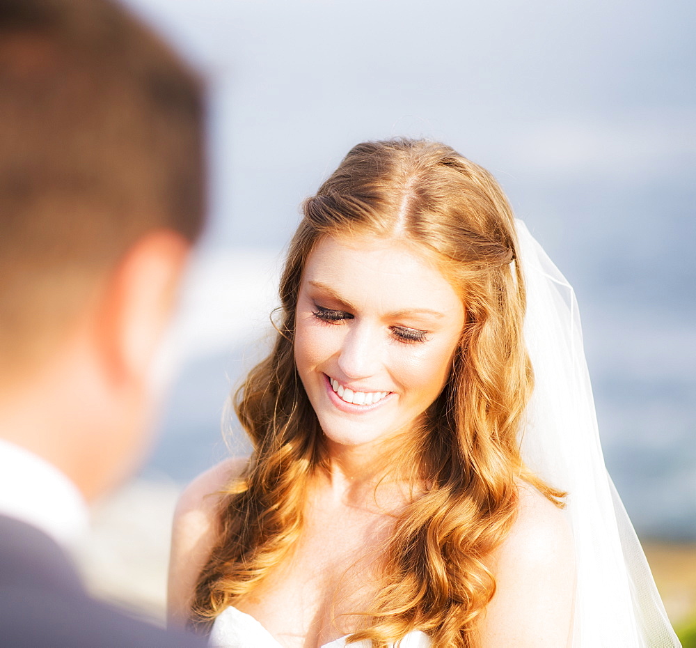 Groom looking at bride, sea in background