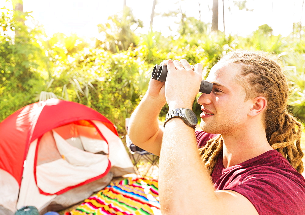 Young man watching birds through binoculars, Tequesta, Florida