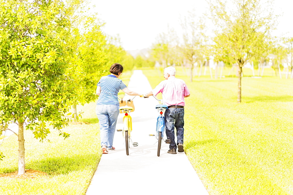 Rear view of couple wheeling bicycles along cycling path, Jupiter, Florida