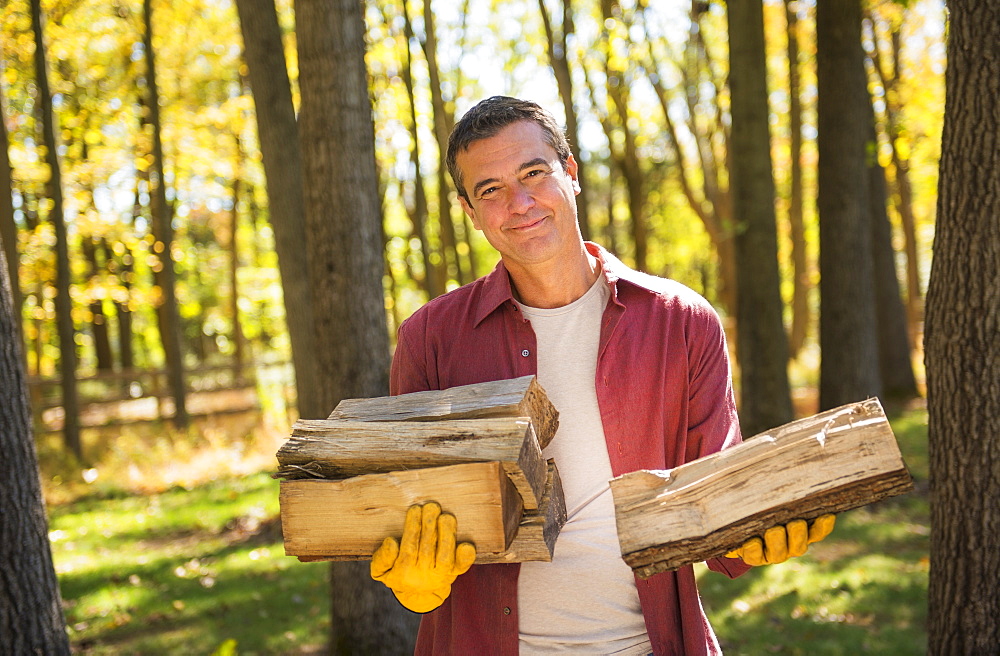 Portrait of man holding armful of logs