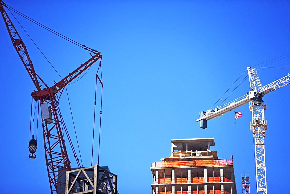 Cranes and high-rise under blue sky