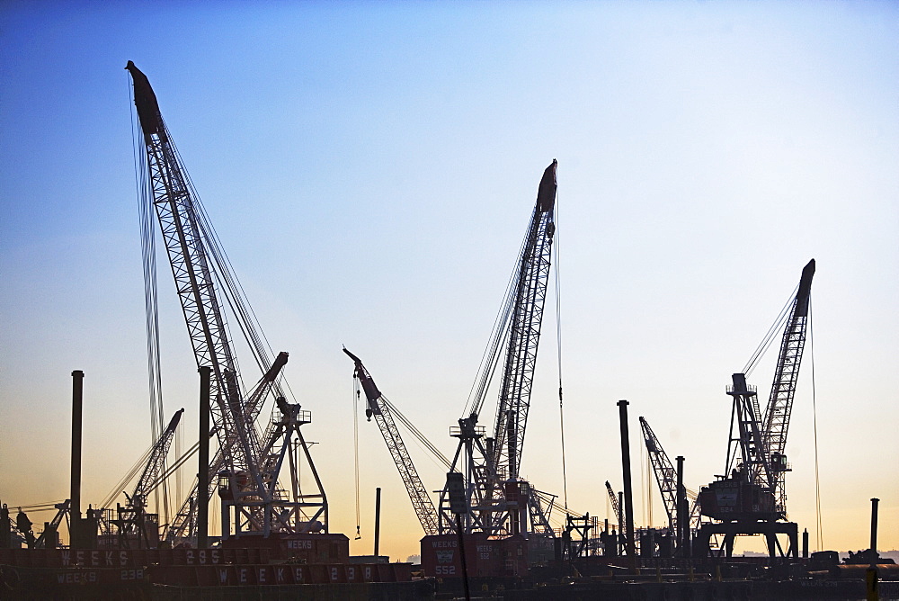 Cranes on dock at sunset