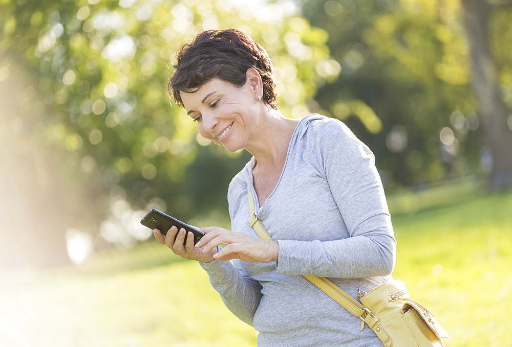 Mature woman text messaging outdoors